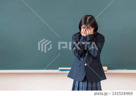 学校の黒板の前で泣く制服姿の小学生,中学生,高校生の女の子 132528469