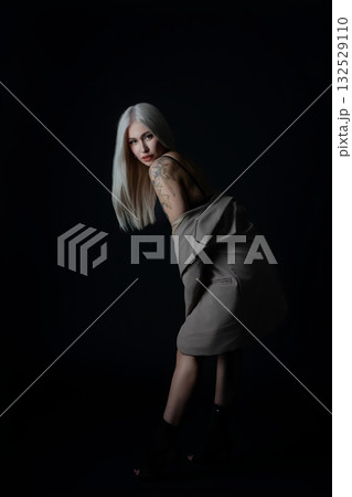 Elegant model posing against a dark background in a stylish outfit Elegant model posing against a dark background in a stylish outfit 132529110