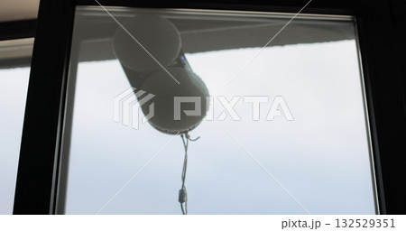 Close up automatic window cleaning robot operating on residential window. Simplicity and convenience of window cleaning. Close up automatic window cleaning robot operating on residential window. Simplicity and convenience of window cleaning. 132529351