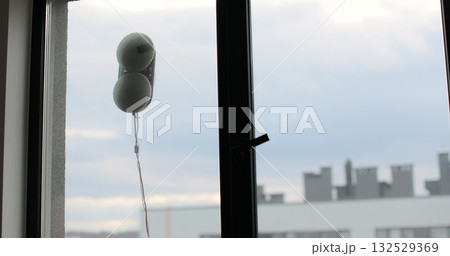 Robot window cleaner washes a window. Cleaning process with modern household appliances. Simplicity and convenience of window cleaning. Robot window cleaner washes a window. Cleaning process with modern household appliances. Simplicity and convenience of window cleaning. 132529369