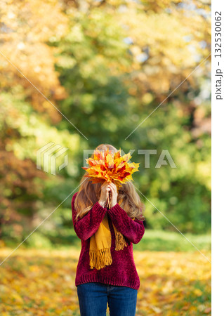 A woman in an autumn park with a bouquet of leaves 132530062