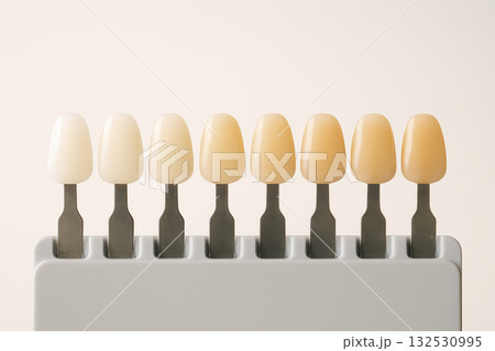 Veneer shade guide with natural tooth color samples arranged in row showing gradient from light to dark for dental matching and aesthetic purposes 132530995