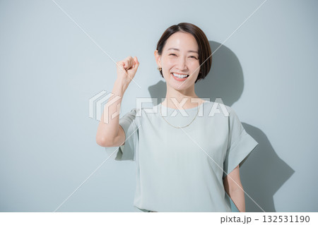 綺麗なミントグリーン背景のビジネス女性イメージ　上半身正面でガッツポーズの応援 132531190