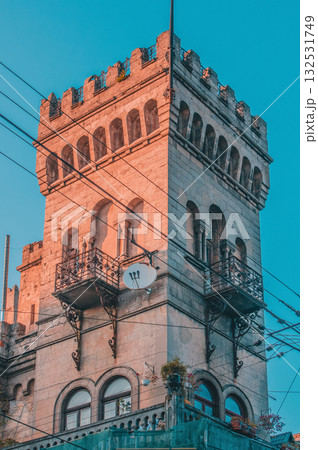The image shows a tall building with architectural features resembling a medieval tower or small castle. It has a rectangular shape with battlements at the top, reminiscent of a crenellated parapet 132531749