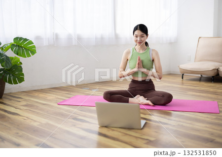 ノートパソコンを使ってオンラインヨガレッスンを受けるミドル女性 ノートパソコンを使ってオンラインヨガレッスンを受けるミドル女性 132531850