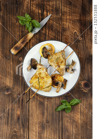 Baked tuna with mushrooms, kebabs on wooden surface. 132531888