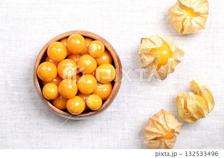 Goldenberries, Peruvian groundcherries, in a wooden bowl, on linen. Ripe and fresh cape gooseberries, also called poha, Physalis peruviana, bright orange fruits, with papery lampion-like husks. Photo Goldenberries, Peruvian groundcherries, in a wooden bowl, on linen. Ripe and fresh cape gooseberries, also called poha, Physalis peruviana, bright orange fruits, with papery lampion-like husks. Photo 132533496