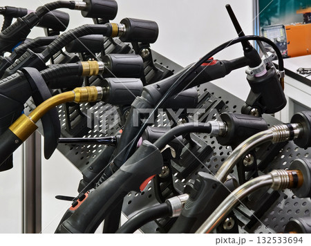 Welding torches and gas hoses displayed on a workbench at a technical exhibition in a workshop setting 132533694