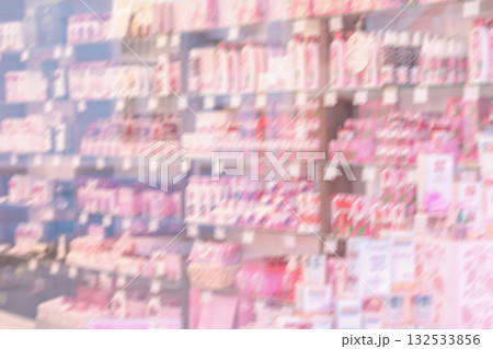 Blurred background through glass of showcase of Bulgarian rose oil cosmetics, perfumes, skincare products arranged on shelves in beauty store. Concept of rose oil beauty, natural cosmetics 132533856