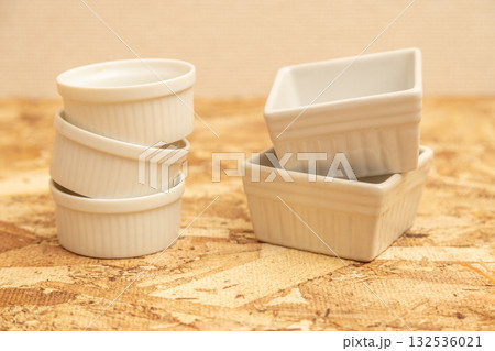 丸と四角のココットがosb合板の上に並べられている　洋風食器の素材写真 132536021