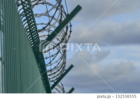 Razor barbed wire on a high security building. Razor wire and heavy-proof wire fencing. The concept of prisons, military facilities, and nuclear power plants. Razor barbed wire on a high security building. Razor wire and heavy-proof wire fencing. The concept of prisons, military facilities, and nuclear power plants. 132536555