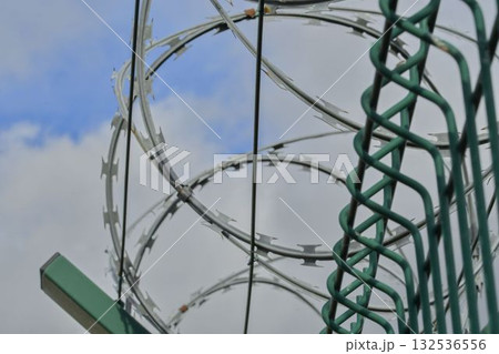 Barbed razor wire on a high-security building. Barbed wire and heavy wire fencing. Design of prisons, military facilities, nuclear power plants, and defense against illegal migration. 132536556