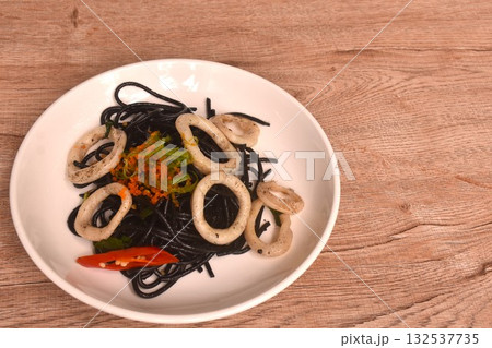 spicy fried black squid ink spaghetti with slice cuttlefish dressing shrimp egg and basil on plate spicy fried black squid ink spaghetti with slice cuttlefish dressing shrimp egg and basil on plate 132537735