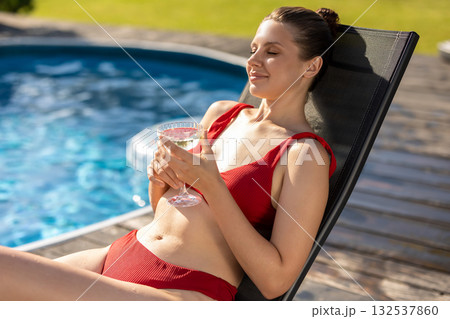 Pretty young woman in red swimsuit sunbathing near the swimming pool Pretty young woman in red swimsuit sunbathing near the swimming pool 132537860