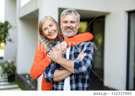 Cute woman in orange shirt hugging her husband and smiling nicely Cute woman in orange shirt hugging her husband and smiling nicely 132537985