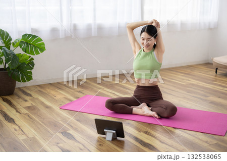 タブレットを見ながらストレッチをするミドル女性 132538065