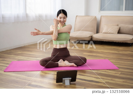 タブレットを見ながらストレッチをするミドル女性 132538066