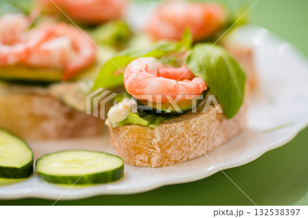Isolated mini canapes with shrimps, lettuce and cucumber, on a green background 132538397