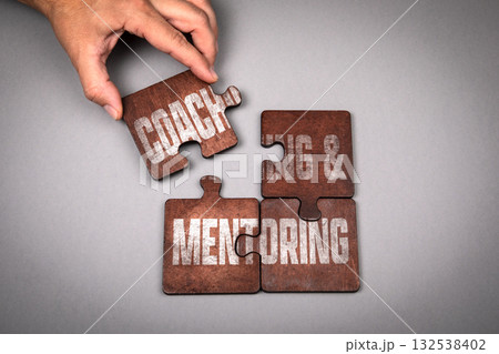 Coaching and Mentoring Concept. Wooden puzzle pieces with text on a gray background Coaching and Mentoring Concept. Wooden puzzle pieces with text on a gray background 132538402