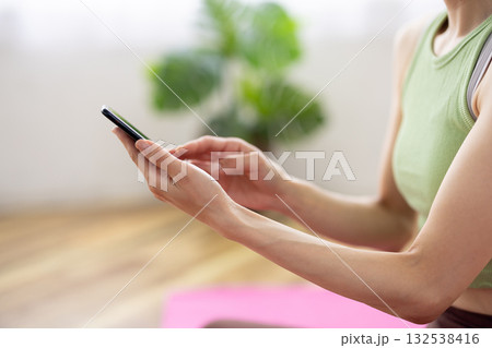 ヨガウェアを着てスマートフォンを操作する女性の手元 132538416