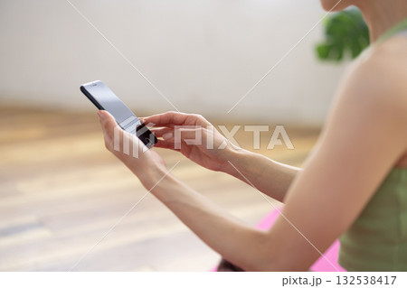 ヨガウェアを着てスマートフォンを操作する女性の手元 132538417