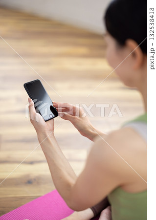 ヨガウェアを着てスマートフォンを操作する女性の手元 132538418
