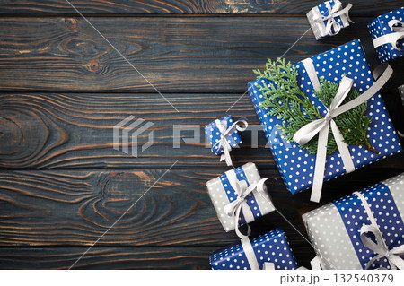 Blue and silver gift boxes with ribbon and thuja on blue wooden background. Copy space Blue and silver gift boxes with ribbon and thuja on blue wooden background. Copy space 132540379