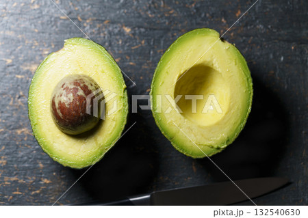 Fresh avocado halves on dark stone background Fresh avocado halves on dark stone background 132540630