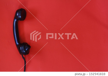 black old telephone receiver hanging on red background with texting space, waiting for phone call, vintage telephone. 132541810