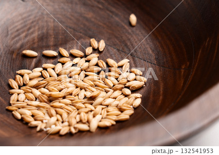 Raw cat grass grains on wooden bowl texture close up 132541953