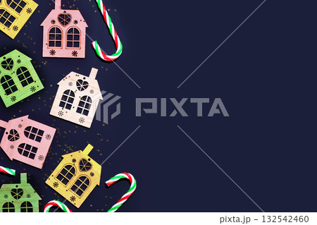 Christmas background with decorative, multicolored, wodden houses, sweets and golden confetti on a deep blue background with place for text. Merry Christmas composition, flat lay Christmas background with decorative, multicolored, wodden houses, sweets and golden confetti on a deep blue background with place for text. Merry Christmas composition, flat lay 132542460