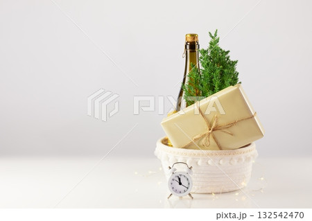 Christmas or New Year, holiday card with Small, home planted Christmas tree, bottle of champaign, candle, gift and clock on a white table with copy space. Zero waste eco Christmas and New Year concept Christmas or New Year, holiday card with Small, home planted Christmas tree, bottle of champaign, candle, gift and clock on a white table with copy space. Zero waste eco Christmas and New Year concept 132542470