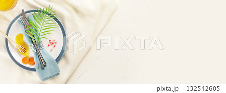 Rosh hashanah, Jewish New Year holiday. Rosh hashanah banner with table setting and traditional symbols, honey, carrots and pomegranate seeds on a white background with copy space. Jewish holidays Rosh hashanah, Jewish New Year holiday. Rosh hashanah banner with table setting and traditional symbols, honey, carrots and pomegranate seeds on a white background with copy space. Jewish holidays 132542605