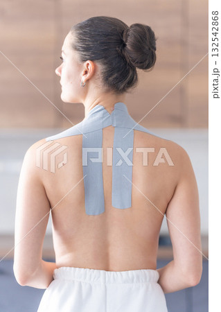 Kinesiology tape applied to the neck and shoulder area of a woman. Physical therapy and muscle support through modern rehabilitation techniques 132542868