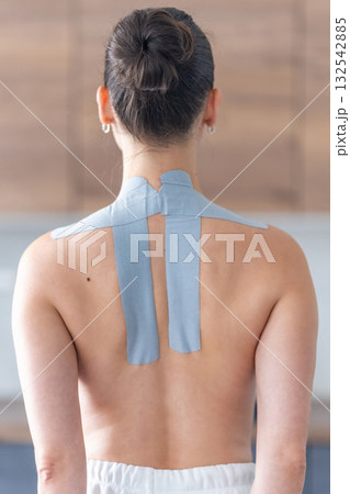 Kinesiology tape applied to the neck and shoulder area of a woman. Physical therapy and muscle support through modern rehabilitation techniques 132542885