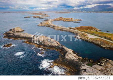 Scenic Atlantic ocean road winds through rugged coastal landscape connecting small islands in calm dark blue waters. Remote and wild beauty of Norway 132544081