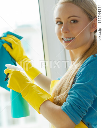 Girl cleaning window at home using detergent rag Girl cleaning window at home using detergent rag 132544354