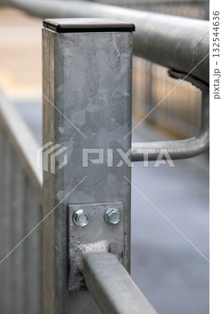 Close up of galvanized steel post with bolts and welded joint on outdoor metal handrail construction 132544636