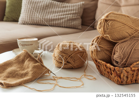 Cozy Living Room with Yarn, Pillows and Cup of Cappuccino on White Table Cozy Living Room with Yarn, Pillows and Cup of Cappuccino on White Table 132545155