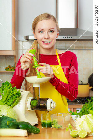 Woman in kitchen making vegetable smoothie juice Woman in kitchen making vegetable smoothie juice 132545297
