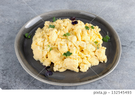 Scrambled eggs with green onions on a gray plate on a gray background. Healthy breakfast. Scrambled eggs with green onions on a gray plate on a gray background. Healthy breakfast. 132545493