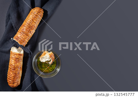 Homemade, natural, wheat bread. Broken fresh, crunchy, french baguette with olive oil on black textile background with copy space. Hand made baking. Healthy, tasty natural product. Mediterranean food 132545777