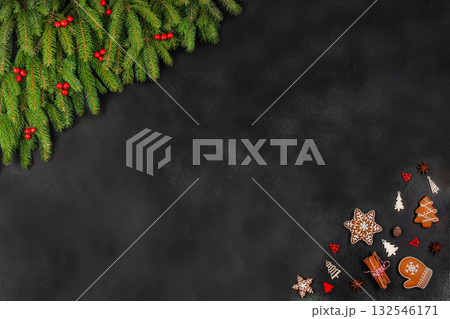 Christmas background with fir branches, red berries, gingerbread cookies and wooden decorations on dark surface, festive flat lay with copy space for text Christmas background with fir branches, red berries, gingerbread cookies and wooden decorations on dark surface, festive flat lay with copy space for text 132546171