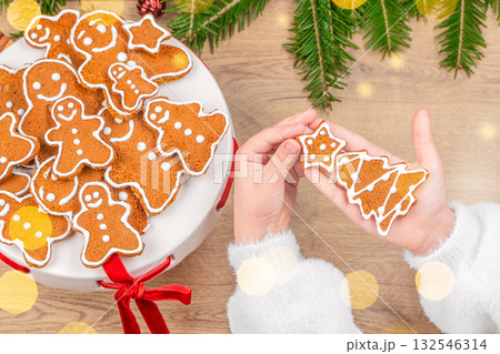 Child holding decorated Christmas gingerbread cookies with festive background and holiday atmosphere top view 132546314