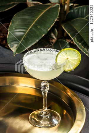 Refreshing margarita cocktail with lime garnish and salted rim served in an elegant glass on a golden tray Refreshing margarita cocktail with lime garnish and salted rim served in an elegant glass on a golden tray 132546323