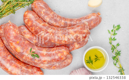 Raw pork sausages with spices, garlic, thyme, and olive oil on light background. Fresh homemade sausage, uncooked meat, organic food ingredient for barbecue and grill Raw pork sausages with spices, garlic, thyme, and olive oil on light background. Fresh homemade sausage, uncooked meat, organic food ingredient for barbecue and grill 132546338