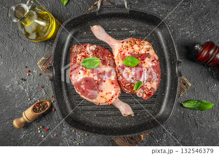 Raw duck legs seasoned with herbs and pepper in a grill pan, ready for traditional confit preparation. top view Raw duck legs seasoned with herbs and pepper in a grill pan, ready for traditional confit preparation. top view 132546379