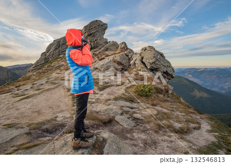 Young child boy hiker taking pictures in mountains enjoying view of amazing mountain landscape. 132546813