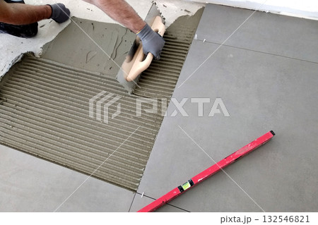 Worker hands putting ceramic tiles on the floorl. Worker hands putting ceramic tiles on the floorl. 132546821