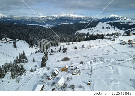 Winter landscape with small rural houses in remote settlement between snow covered forest in cold mountains 132546845
